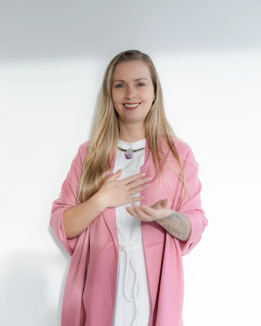 Lairany Souza sorrindo, de xale rosa, com a mão sobre o coração
